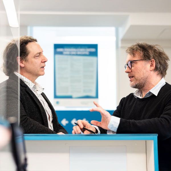 Zwei Personen stehen sich gegenüber und sprechen im Innenraum