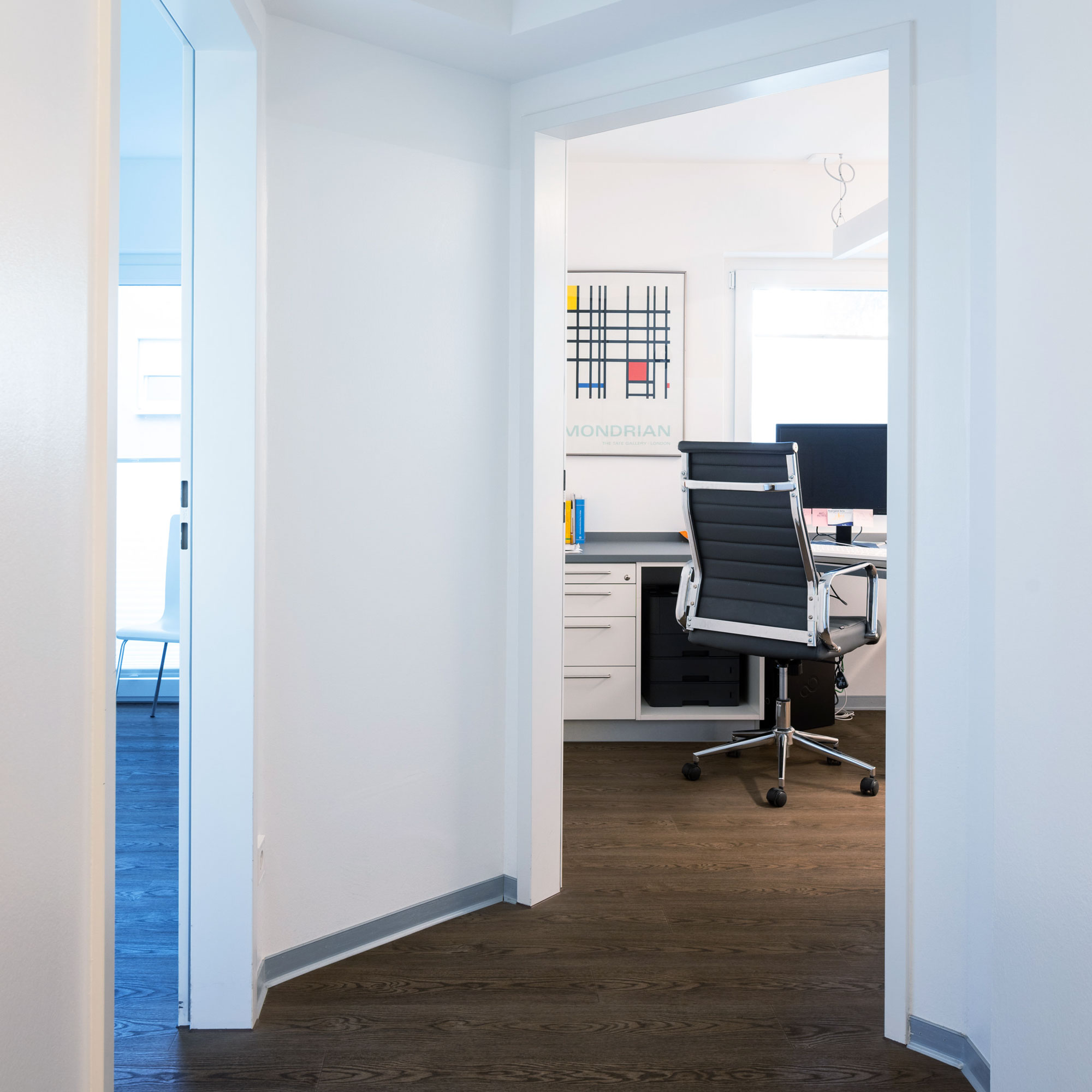 Blick durch Türrahmen in Büro mit Schreibtisch und Bürostuhl